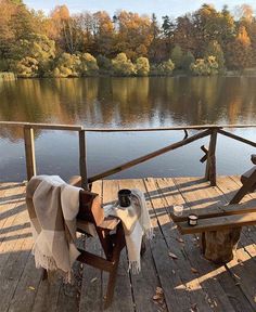 a wooden deck with a table and chair on it next to a body of water