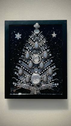 a glass christmas tree is on display in a black frame