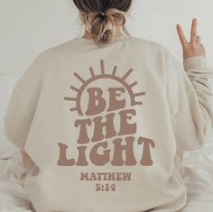 Be The Light Sweatshirt Gift For Christians, Mathew 5:14 Sweatshirt, Bible Verse Sweatshirt IMPORTANT NOTE: - Because of high season, there are some colors runs out of stock, we will contact you if that color is out-stock - The images on the website is only sweatshirt/ shirt, please click on the style box to choose the style you love because there are many kinds of apparels: t-shirt, sweatshirt, hoodie, long sleeve (the long sleeves is not sweatshirt but long sleeves shirt) PRODUCT INFORMATION - All sizes are Unisex. - Design will either be white or black depending on the shirt color. - Uses a vinyl which is then pressed using an industrial heat press. It is machine washable however it is recommended to turn inside out while washing. - Keep in mind that colors may differ depending on compu Things To Put On Sweatshirts, Biblical Sweatshirts, Be The Light Sweatshirt, Be The Light Shirt Design, Cute Christian Sweatshirt Designs, Gift Ideas For Christians, Christian Sweatshirts Hoodie, Cute Sweatshirts Christian, Cute Aesthetic Sweatshirts