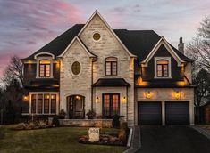 a large house with two garages and lights on