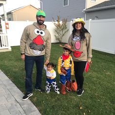 a man, woman and child dressed up in costumes standing on the grass near a house