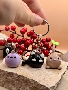 a hand holding a keychain with three small toy animals on it