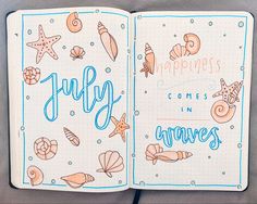 an open notebook with the words july written in blue ink and seashells on it