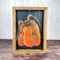 a small wooden frame with a painting of two pumpkins on top of each other