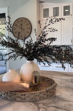 a vase filled with flowers sitting on top of a table next to a candle and clock