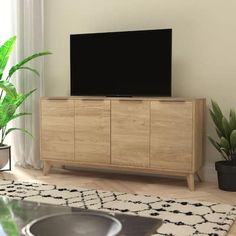 a living room with a large television on top of a wooden cabinet next to potted plants