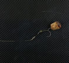 a piece of metal with some wire attached to it on a black background that looks like carbon fiber