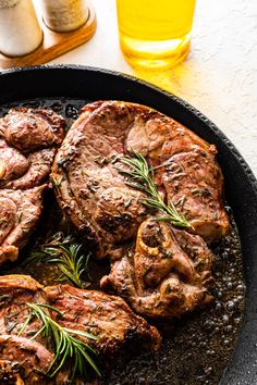 steaks in a skillet with rosemary garnish