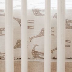 a baby crib with white sheets and brown birds on it