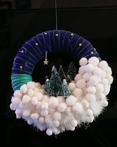 a christmas wreath hanging from the ceiling with white balls and trees on it's side