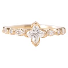 a yellow gold ring with an oval cut diamond in the center and leaves on each side