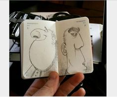 a hand is holding an open notebook with drawings on it and the pages have been drawn