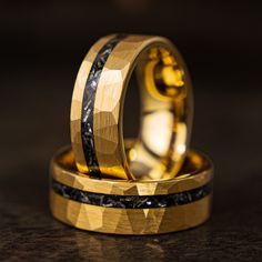 two gold wedding rings with black and white marble inlays on top of each other