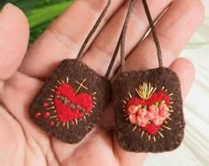 two brown felt heart shaped ornaments hanging from strings