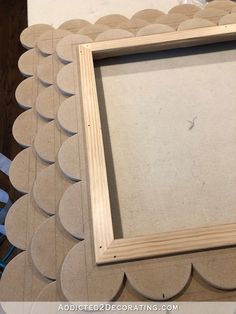 a wooden frame sitting on top of a table next to some scissors and paper circles