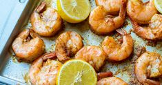 cooked shrimp with lemon wedges on a baking sheet