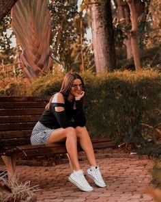 a woman is sitting on a bench in the park