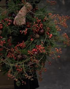 a wreath with red berries and pine cones