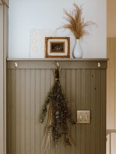 there is a coat rack on the wall with flowers and plants in front of it