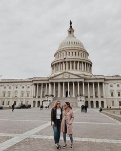 two women standing in front of the u s capitol building on a cloudy day,