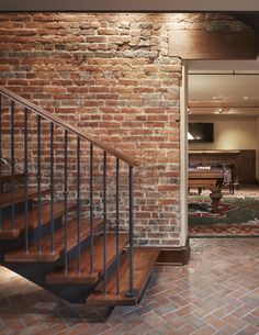 a brick wall with stairs leading up to a living room and kitchen area in the background