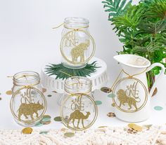 four glass jars with gold glittered animals on them and one has a monogrammed giraffe in the middle