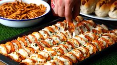 a person is cutting up food on a platter with other foods in bowls behind them