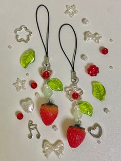 some fruit charms are laying on a white surface with silver earwires and beads