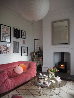 a living room with pink couches and pictures on the wall above it's fireplace