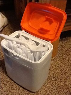 an orange and white container filled with toothbrushes on top of a carpeted floor