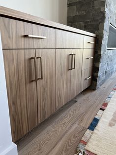 a large wooden cabinet sitting on top of a hard wood floor next to a stone wall