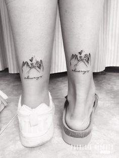 black and white photo of two legs with small tattoos on their ankles, one is holding the other's leg