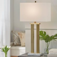 a lamp that is on top of a table next to a vase with a plant