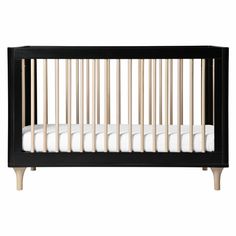 a black crib with white sheets and wooden slats on the bottom, in front of a white background