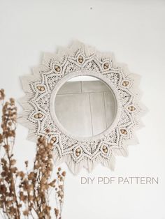 a white mirror sitting on top of a wall next to dried flowers and a plant