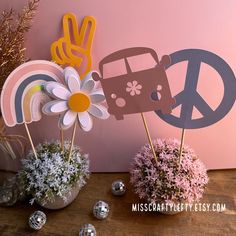 there are flowers in vases with peace sign and car on the stick next to them