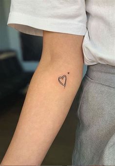 a woman's arm with a small heart tattoo on the left side of her arm