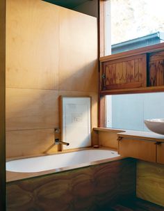 a bath tub sitting under a window next to a wooden counter top and sink in a bathroom