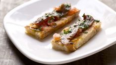 two pieces of bread on a plate with parsley and tomato toppings, ready to be eaten