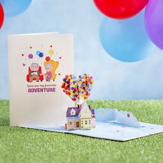 there is a card with balloons and a house on it next to some other cards