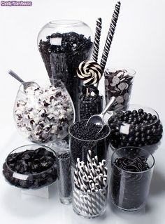 an assortment of candies and chocolates in glass containers on a white table top