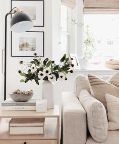 a living room filled with furniture and flowers on top of a coffee table in front of a window