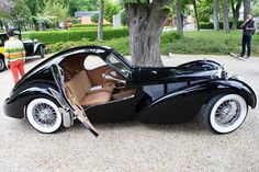 an old black car parked next to a tree