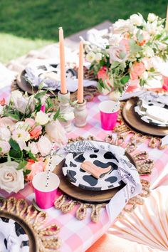 the table is set with black and white plates, pink napkins, and candles