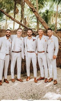 a group of men standing next to each other wearing white suits and brown shoes with palm trees in the background