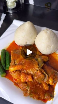 a white plate topped with meat covered in sauce and veggies next to rice