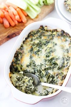 a casserole dish with spinach and carrots on the side, ready to be eaten