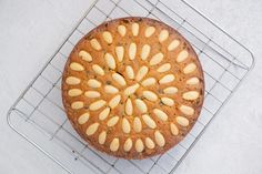 a cake with almonds on top sitting on a cooling rack