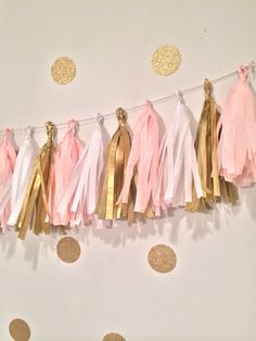 pink and gold tassels hanging from a string on a white wall with polka dots