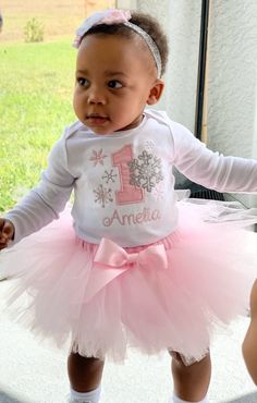 a baby girl wearing a pink tutu and white shirt with the number one on it